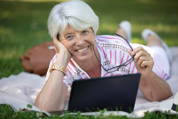 年配の女性が公園でラップトップを使用して — ストック写真