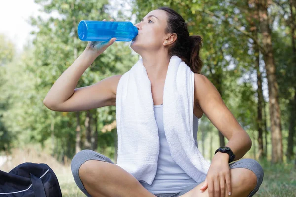 公園に座って水を飲む美しい女性 — ストック写真