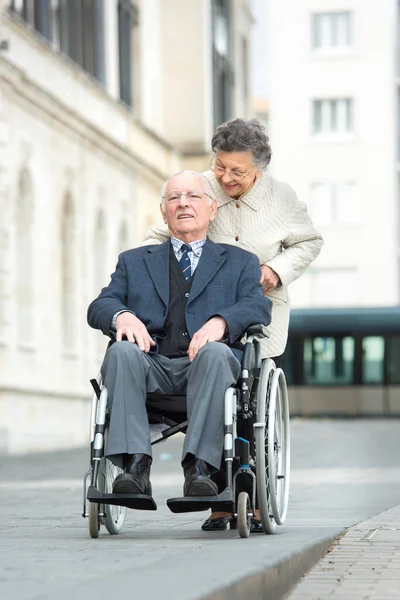 高齢の女性が障害者の夫を車椅子に押しつけて — ストック写真