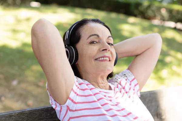 Caucasianシニア女性幸せなで公園とともにヘッドフォン — ストック写真