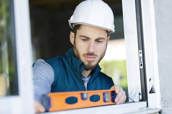 Junger Männlicher Arbeiter Überprüft Das Niveau Eines Fensters — Stockfoto