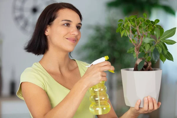 陽気な若い女性が植物を噴霧し — ストック写真