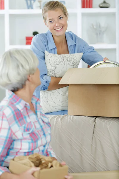 Mulher Segurando Caixa Papelão Ajudando Mãe Desempacotar Coisas — Fotografia de Stock