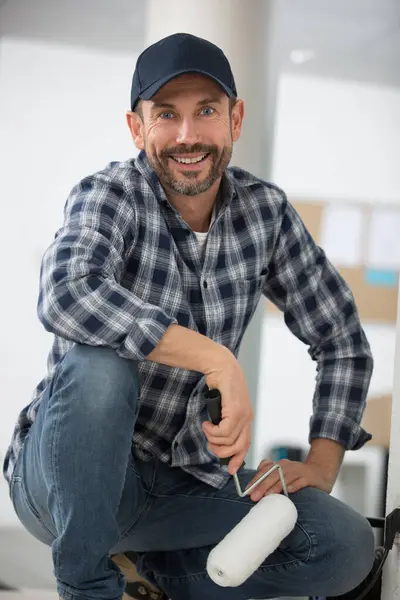 Crouching Male Decorator Holding Paint Roller — Stock Photo, Image