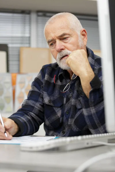 Kontemplativ Senior Man Som Arbetar Vid Skrivbordet — Stockfoto