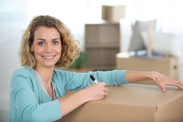 快乐的女人在家里贴上移动盒子的标签 — 图库照片