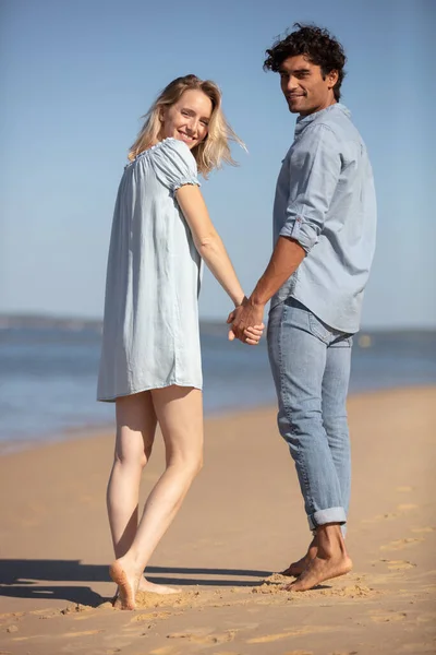 年轻夫妇手牵手走在海滨后视镜上 — 图库照片