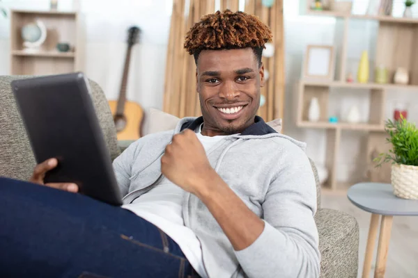 一个在家里做平板电脑的笑脸男人 — 图库照片