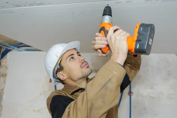 若い労働者が天井を掘削 — ストック写真