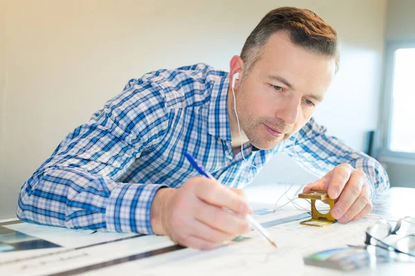 Worker Using Magnifying Device While Wearing Earphones — Stock Photo, Image