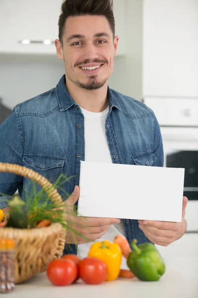 Ευτυχισμένος Νεαρός Που Δείχνει Ένα Πανό Στην Κουζίνα — Φωτογραφία Αρχείου