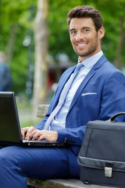 Dışarıdaki Bankta Dizüstü Bilgisayarı Olan Yakışıklı Genç Adam — Stok fotoğraf