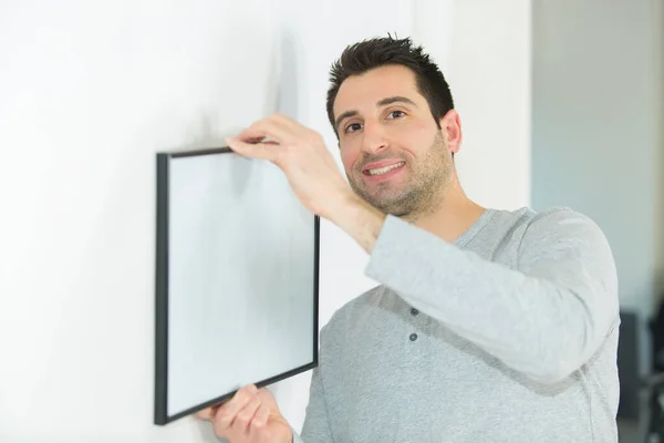 Happy Man Hanging Picture Frames Wall Home — Stock Photo, Image