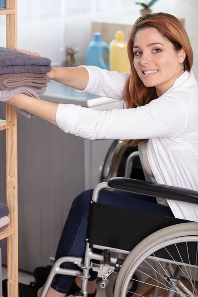 Kobieta Wózku Inwalidzkim Trzyma Złożone Ręczniki Pralni — Zdjęcie stockowe