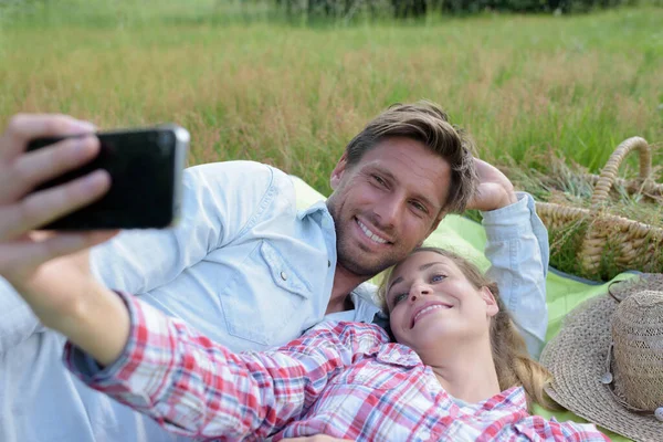 Para Biorąc Selfie Ułożone Kocu Trawie — Zdjęcie stockowe