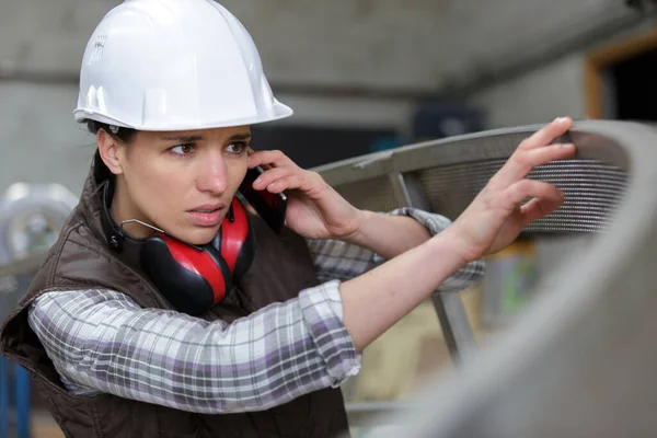 年轻工程师妇女与安全坚硬帽子谈话在电话 — 图库照片