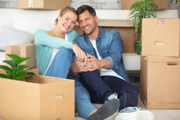 夫妻俩坐在新公寓的地板上 围着纸板箱 — 图库照片