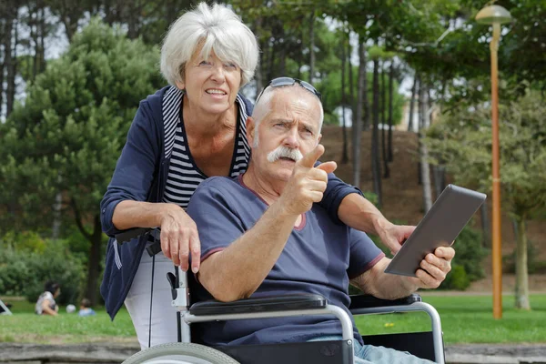 高齢者のカップル屋外で車椅子のタブレットPcの男と — ストック写真