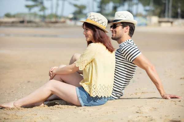 一对年轻夫妇坐在海滩上度假 — 图库照片