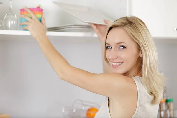Красивая Женщина Тянется Посудой Кухонного Шкафа — стоковое фото