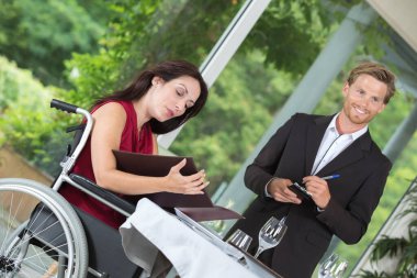 woman in wheelchair choosing the dish from the menu clipart