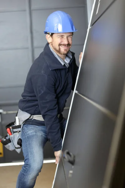 Profesjonalny Stolarz Próbuje Przesunąć Ciężkie Metalowe Drzwi — Zdjęcie stockowe