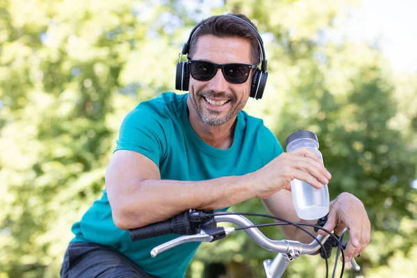 Mężczyzna Rowerze Nosi Słuchawki Trzyma Butelkę Wody — Zdjęcie stockowe