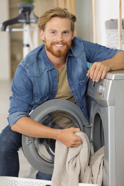 洗濯機の横にあるランドリー バスケットを持つ男 — ストック写真