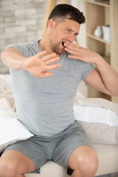 Man Pyjama Stretching Terwijl Zitten Bed — Stockfoto