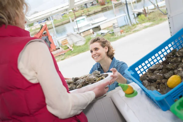 牡蠣売り籠を女性客に渡す — ストック写真