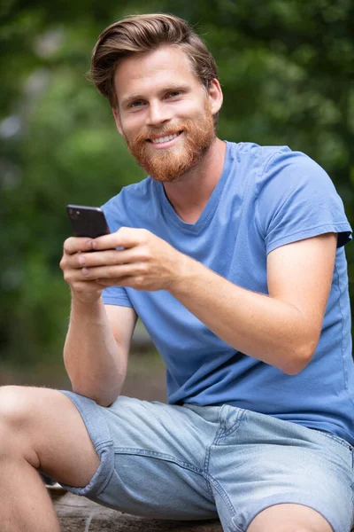 Νεαρός Άνδρας Στην Ύπαιθρο Χρησιμοποιώντας Ένα Smartphone — Φωτογραφία Αρχείου