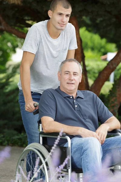 公園の車椅子に座っていた息子と父親は — ストック写真