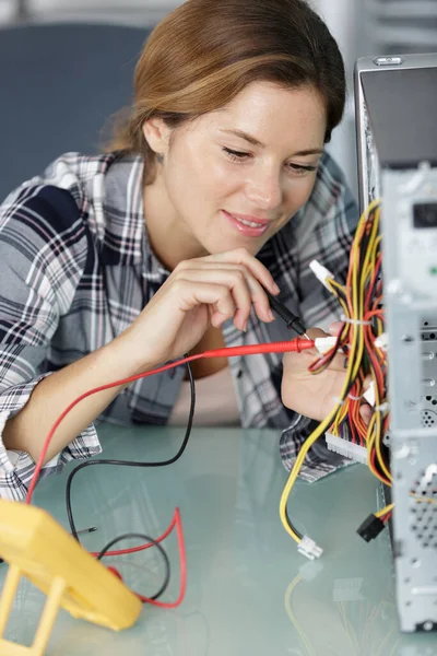 女性技術者がコンピュータをマルチメーターでテストし — ストック写真
