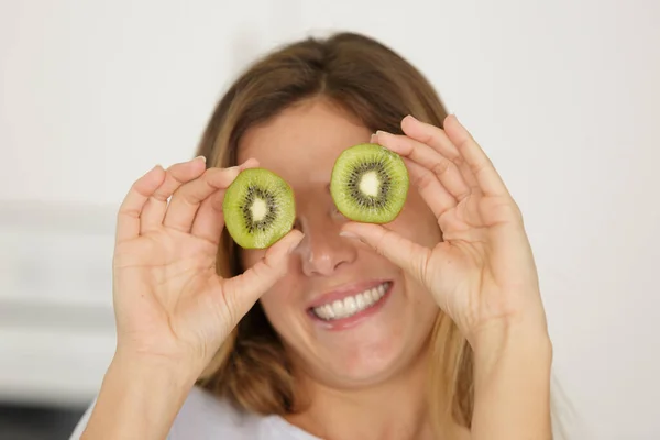 Jovem Senhora Comicamente Segurando Kiwi Fatias Sobre Seus Olhos — Fotografia de Stock