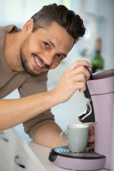 若い男がキッチンでコーヒーを作っていて — ストック写真