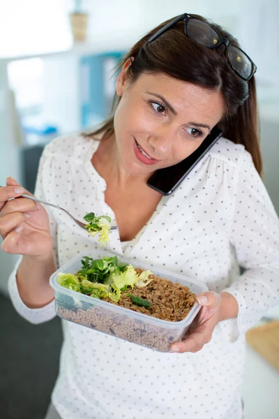 Zajęta Kobieta Jedząca Lunch Balansowaniem Telefonu Ramieniu — Zdjęcie stockowe