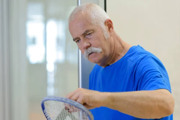 Senior Man Inspecteert Racket Voor Wedstrijd — Stockfoto