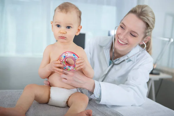 赤ん坊を調べる医者はおもちゃで気を散らし — ストック写真