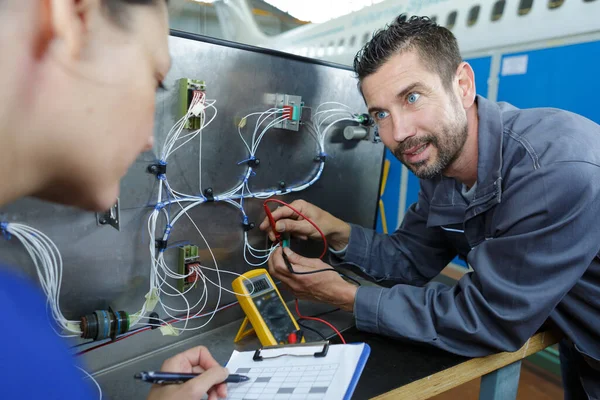 配電盤の電圧を測定する女性と男性の電気技師は — ストック写真