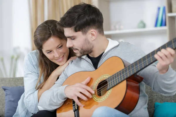 Pareja Abrazando Sofá Mientras Hombre Jugando Guitarra Casa —  Fotos de Stock