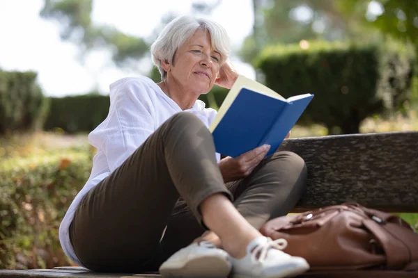 退休妇女在长椅上看书 — 图库照片