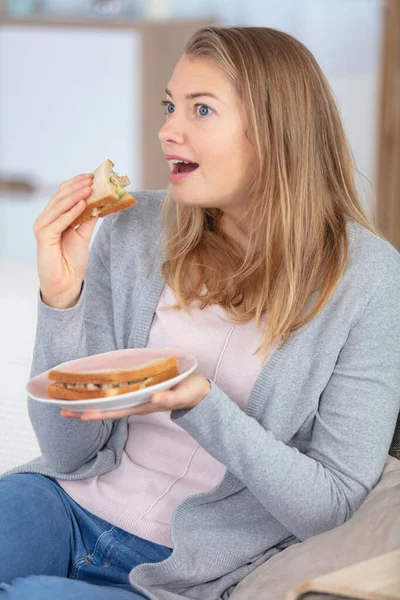 Complacida Mujer Sentada Sofá Comiendo Sándwich —  Fotos de Stock