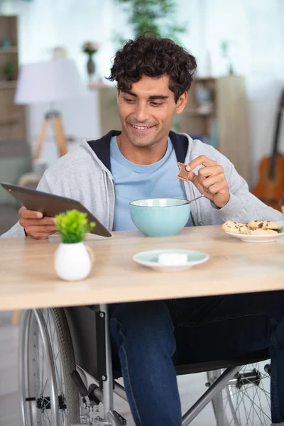Man Wheelchair Eating Breakfast Looking Tablet — Stock Photo, Image