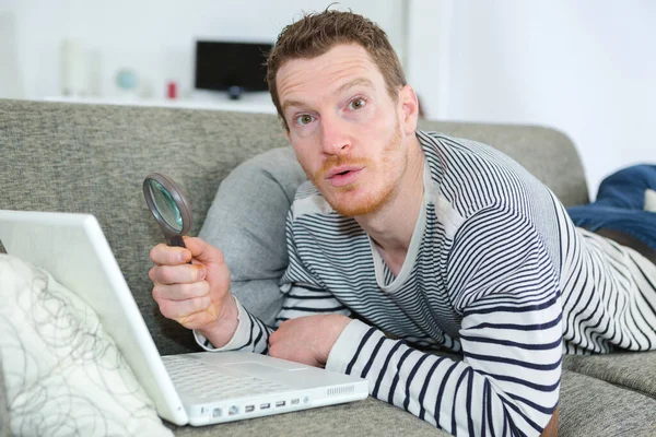 Homem Surpreso Olhando Para Seu Laptop Com Uma Lupa — Fotografia de Stock
