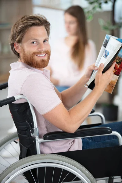 Νέος Άντρας Αναπηρικό Καροτσάκι Διαβάζοντας Ένα Βιβλίο Στο Σπίτι — Φωτογραφία Αρχείου