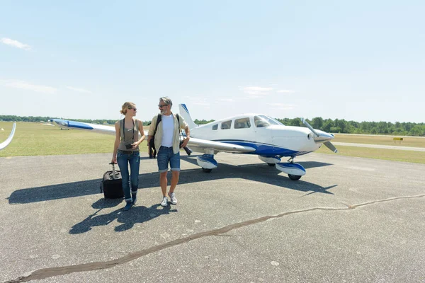 荷物を持ったプライベート飛行機から歩く流行の若いカップル — ストック写真