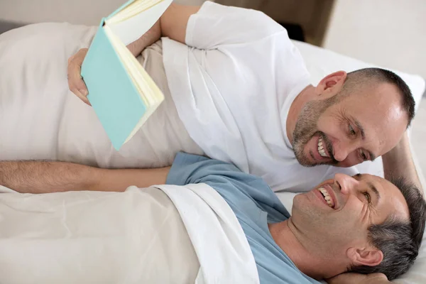 Men Lying Bed Together While Looking Reading Book — 스톡 사진