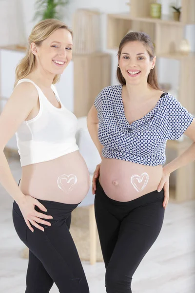 Dos Mujeres Embarazadas Con Corazones Crema Dibujados Sus Protuberancias — Foto de Stock