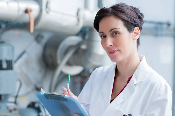 Woman Wearing Labcoat Holding Clipboard Industrial Setting — Stock Photo, Image