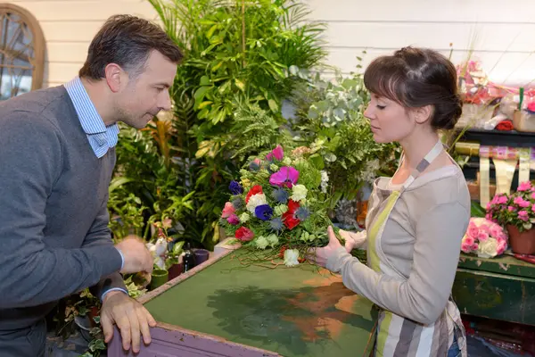 売り手は男性の顧客が花を選ぶのを助け — ストック写真